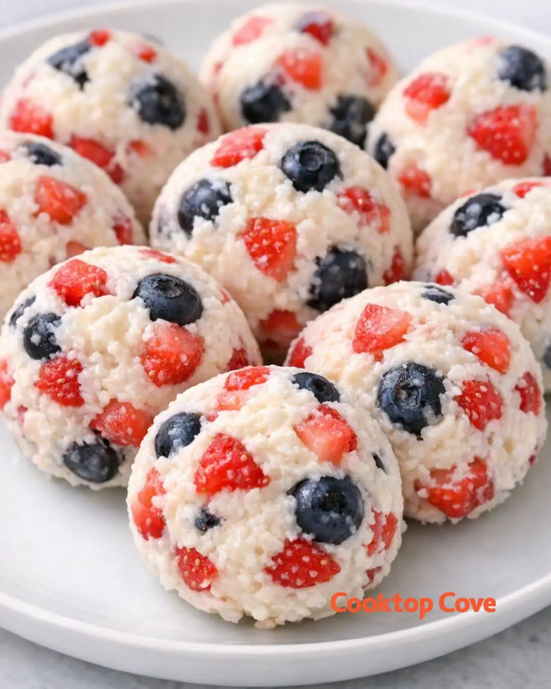 Cremige Beeren Cheesecake Bomben mit Erdbeeren und Blaubeeren auf einem weißen Teller angerichtet.