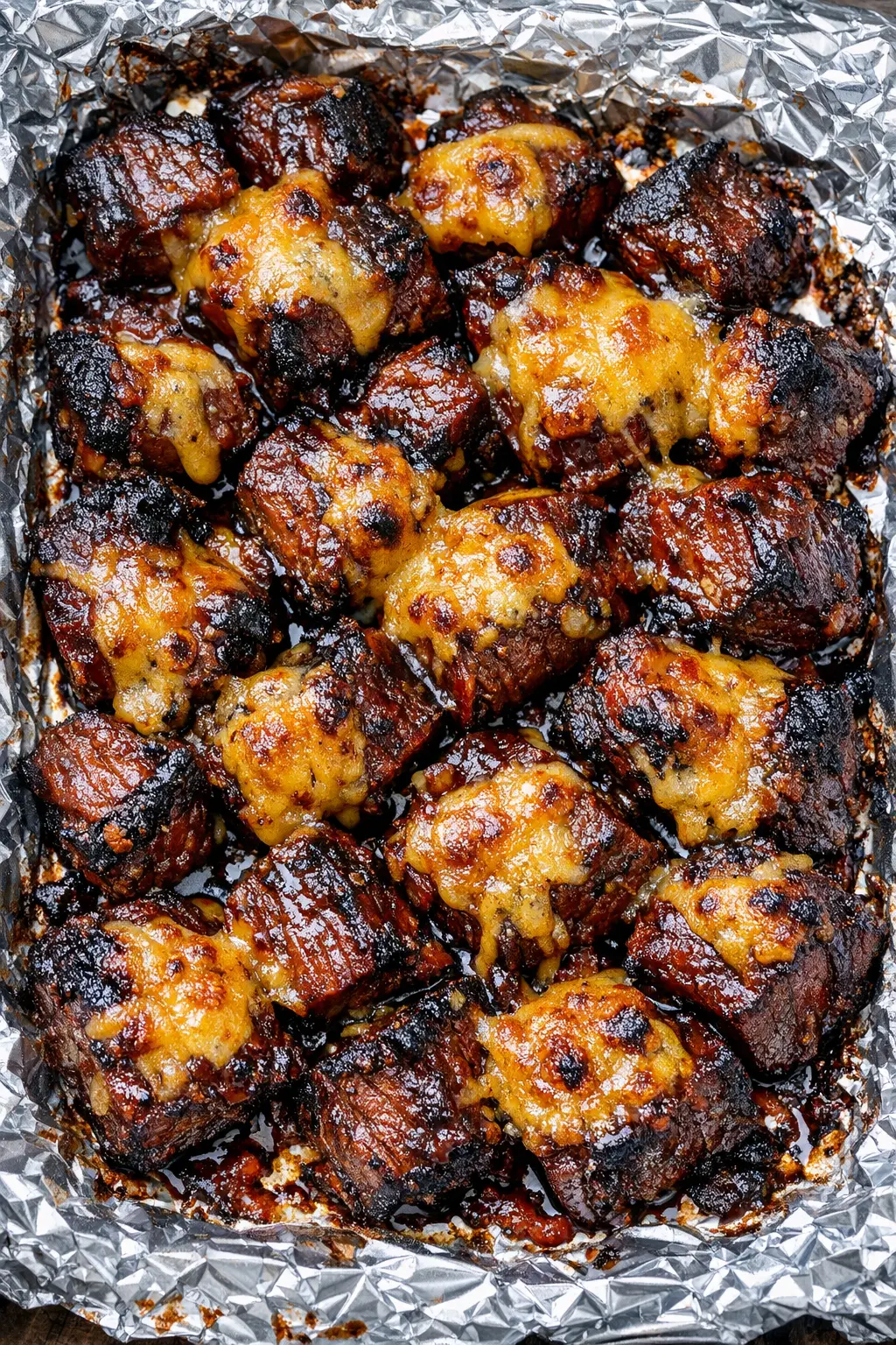 Saftige Brisket Bites mit BBQ-Sauce und geschmolzenem Cheddar frisch aus dem Ofen serviert.